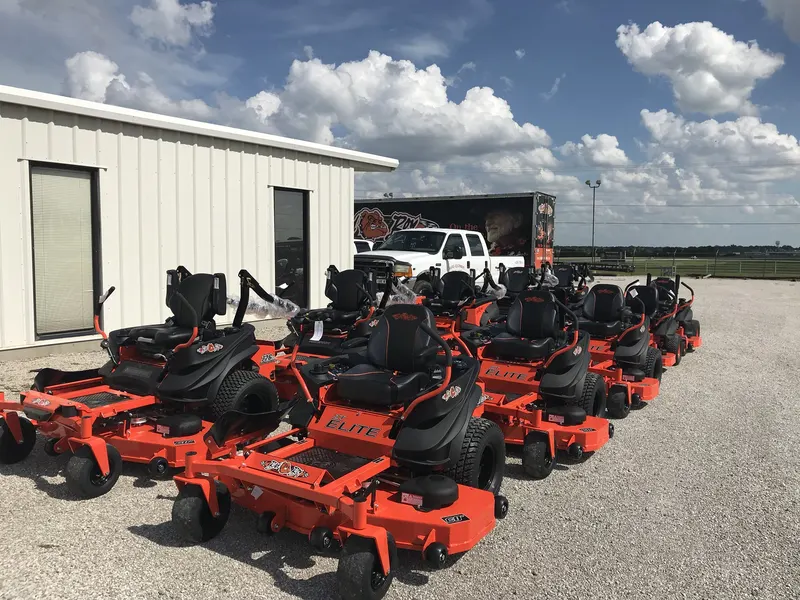 Row of Bad Boy ZT Elite zero turn mowers outside Hayes Equipment with the Bad Boy trailer behind